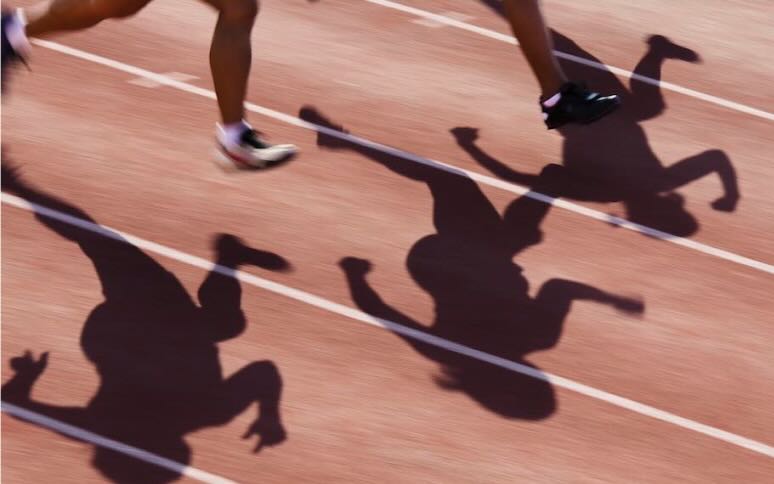 Runners shadows cast on track with lines